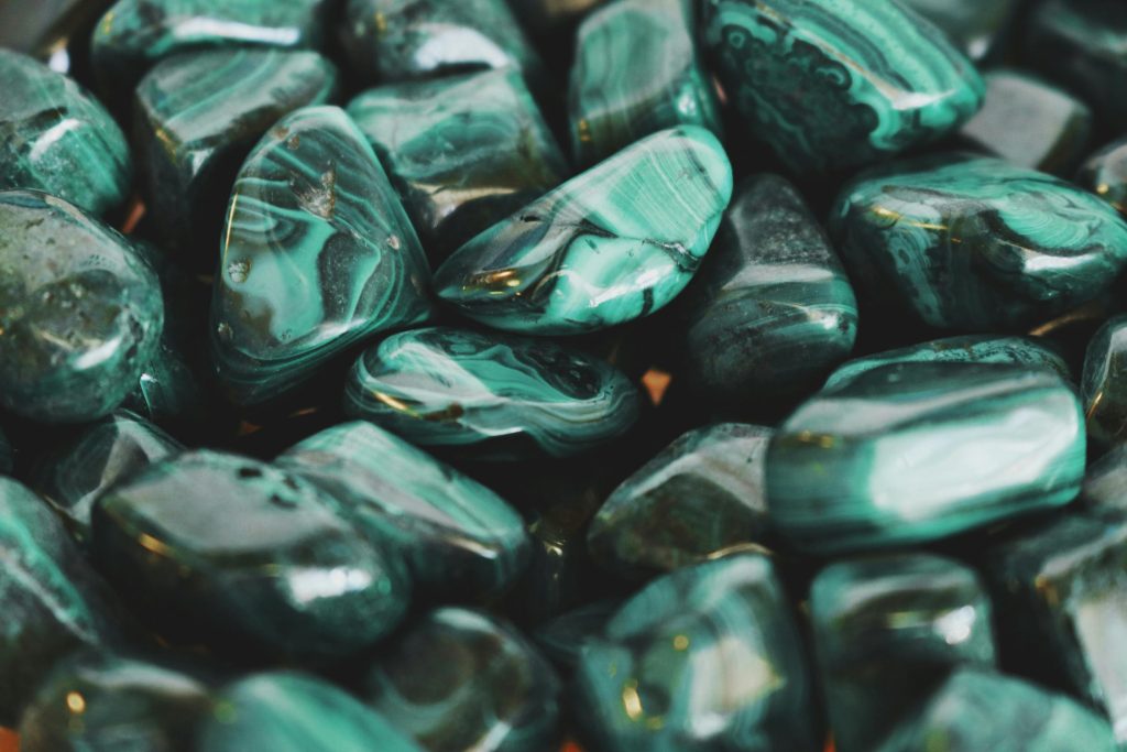 Close-up of polished malachite stones showcasing intricate patterns and vibrant green hues.